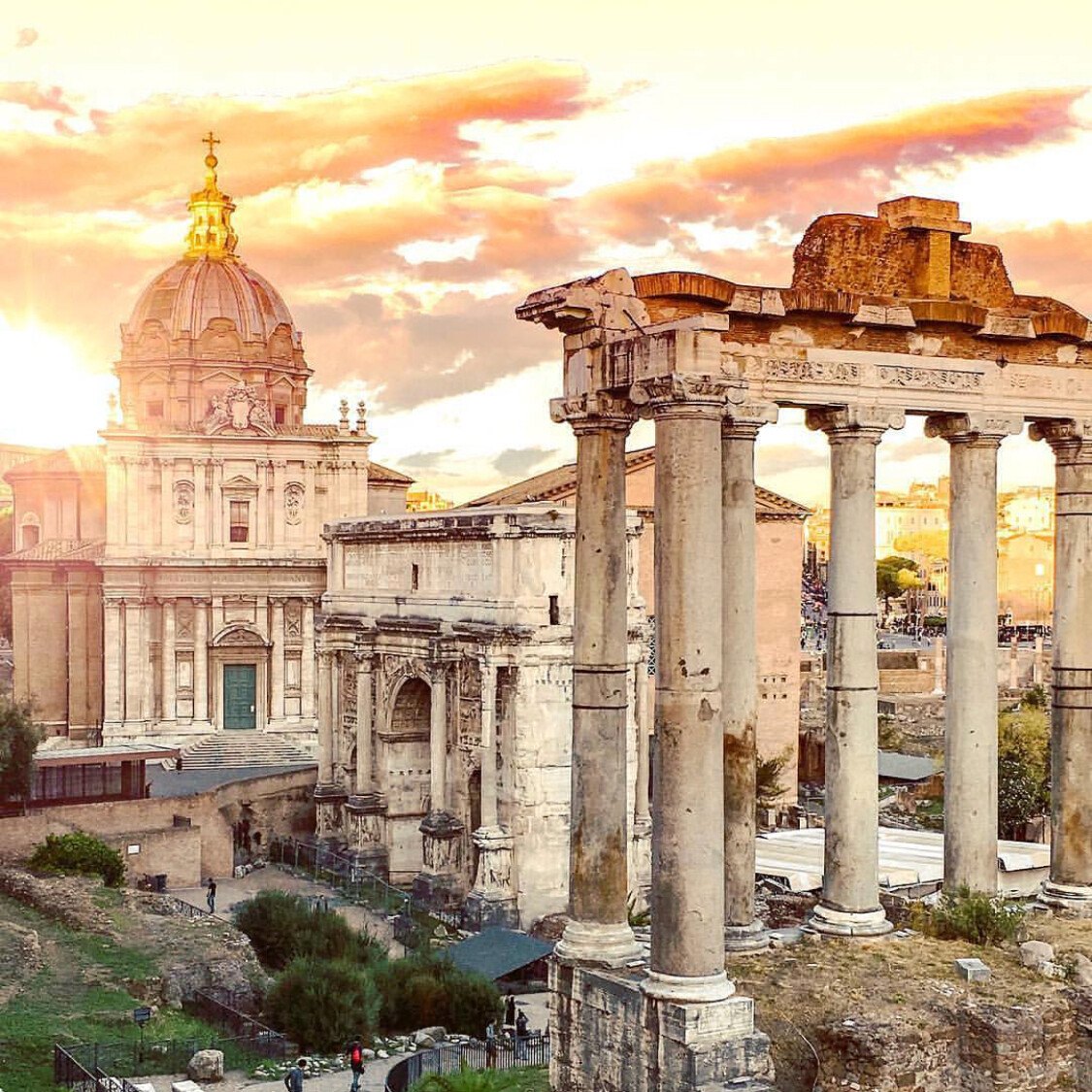 Roman Forum ruins with ancient columns and a triumphal arch at sunset
