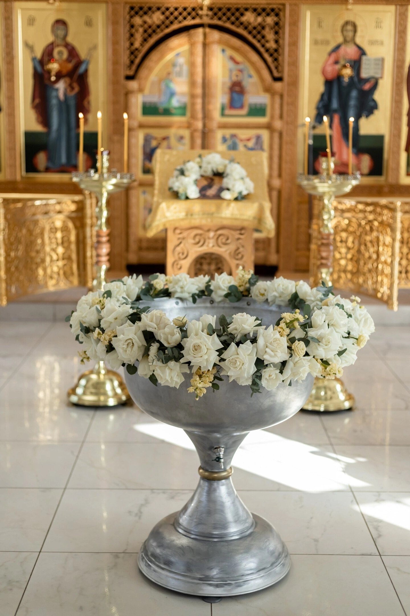 Baptismal font wreathed with white roses inside a church