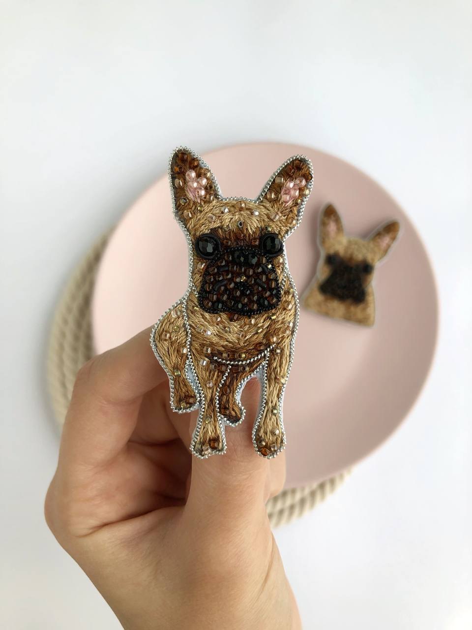 Hand holding an embroidered beaded French bulldog brooch