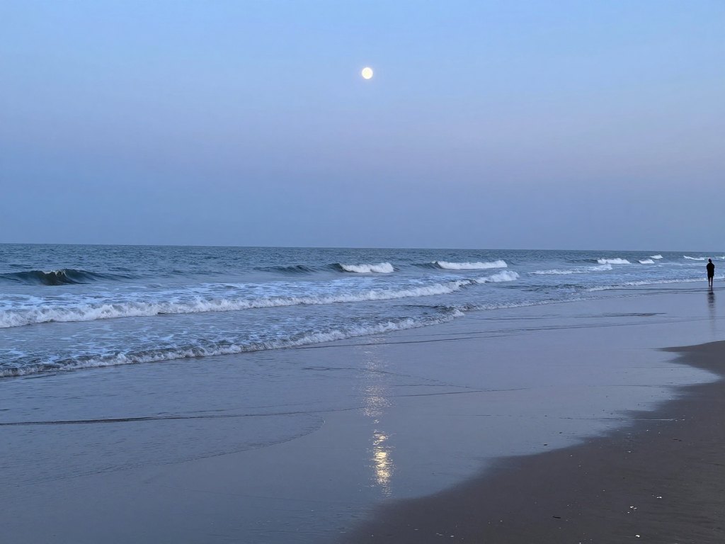 Quiet shoreline at dusk with rippled wet sand and a crescent moon above the sea