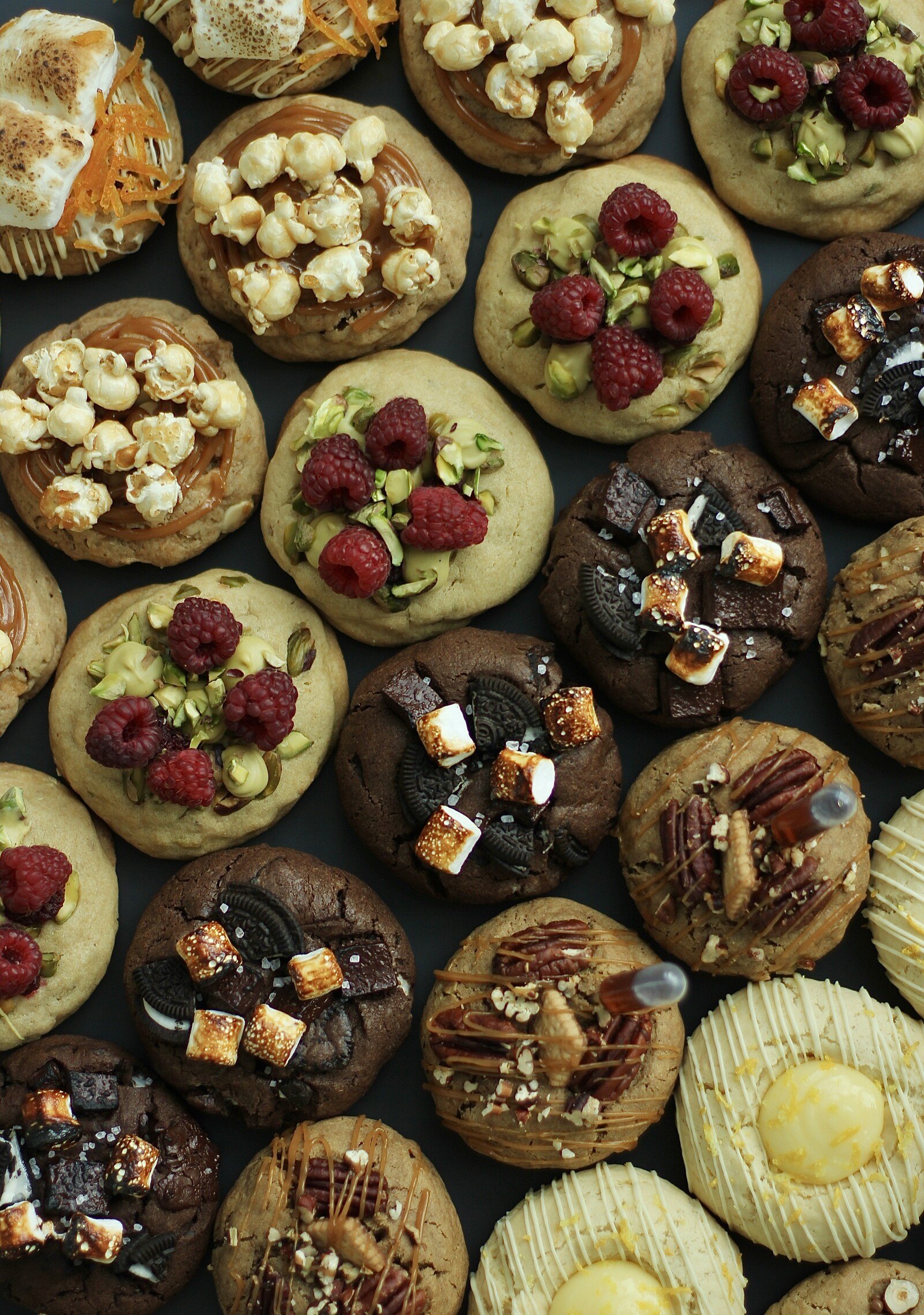Overhead view of assorted decorated cookies with raspberries, marshmallow and lemon glaze