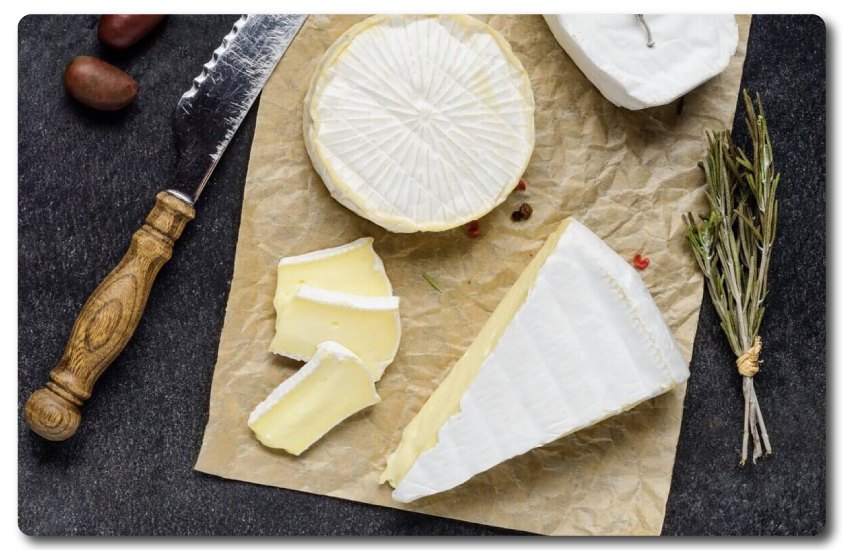 Soft cheeses, slices and a wedge on parchment with a knife and rosemary