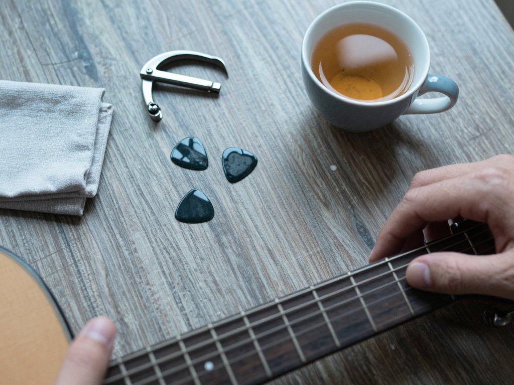 Guitar neck, capo and a cup of tea on a wooden table