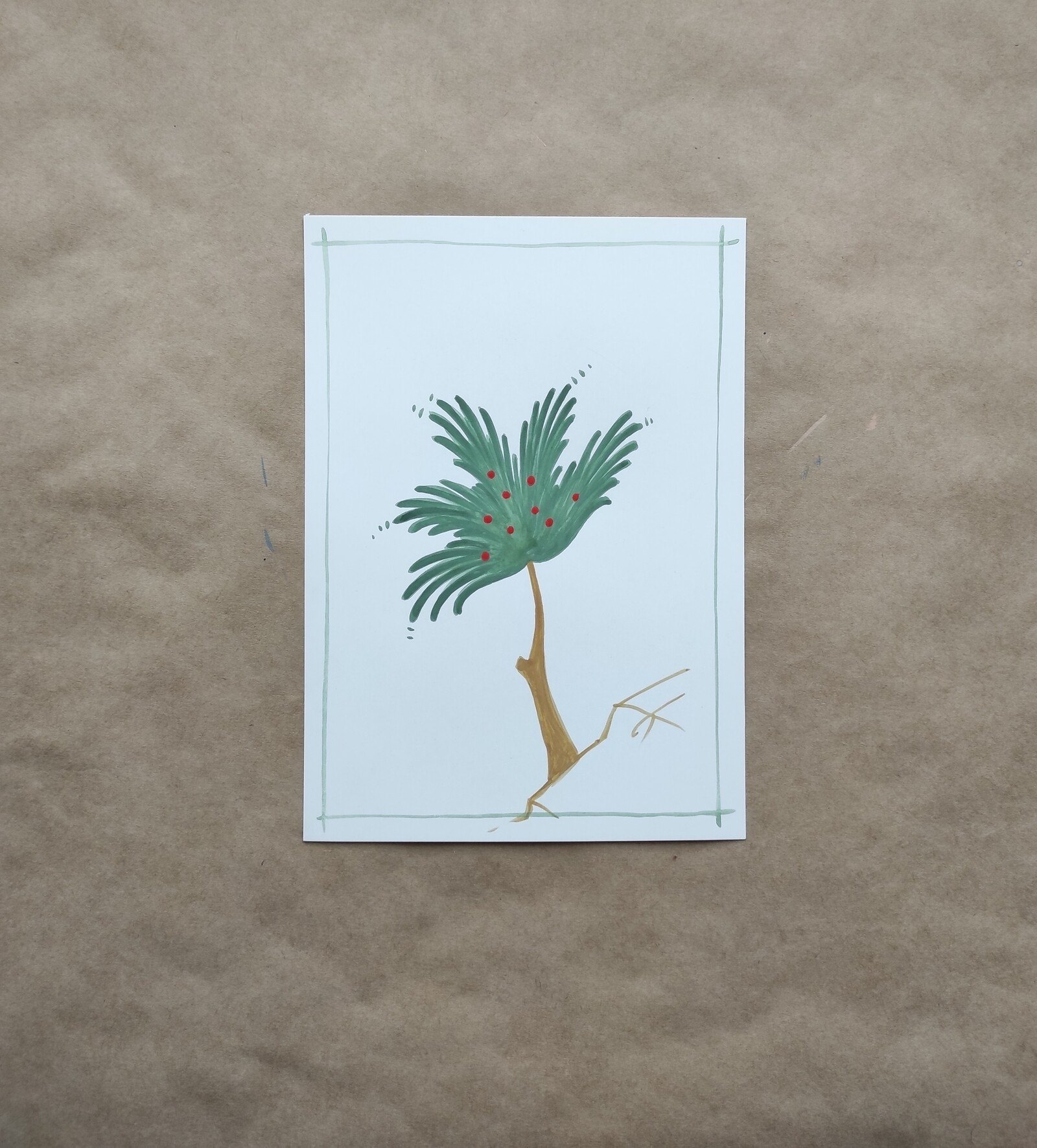 Painted stylised palm tree with red berries on paper over a kraft background