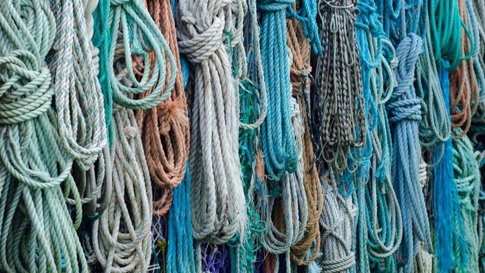 Many coiled ropes in teal, blue, beige and brown hanging together