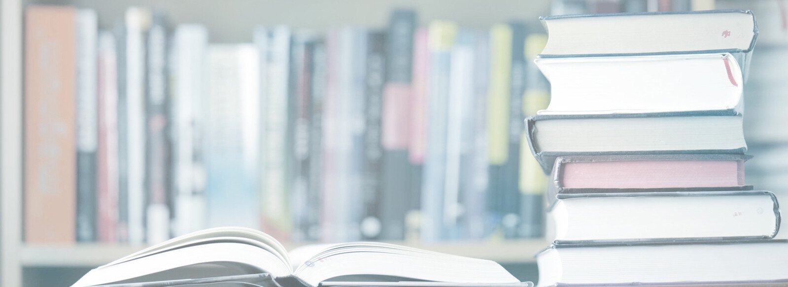 Stack of books beside an open book in a library