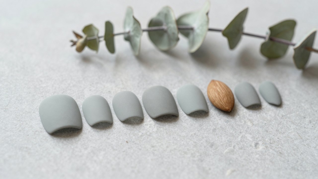 Row of practice nail tips in different shapes on a grey stone surface