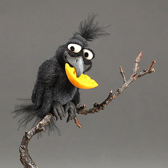 Needle-felted black crow perched on a branch holding a piece of yellow cheese in its beak