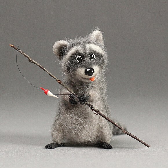 Needle-felted grey raccoon holding a twig fishing rod with a red float
