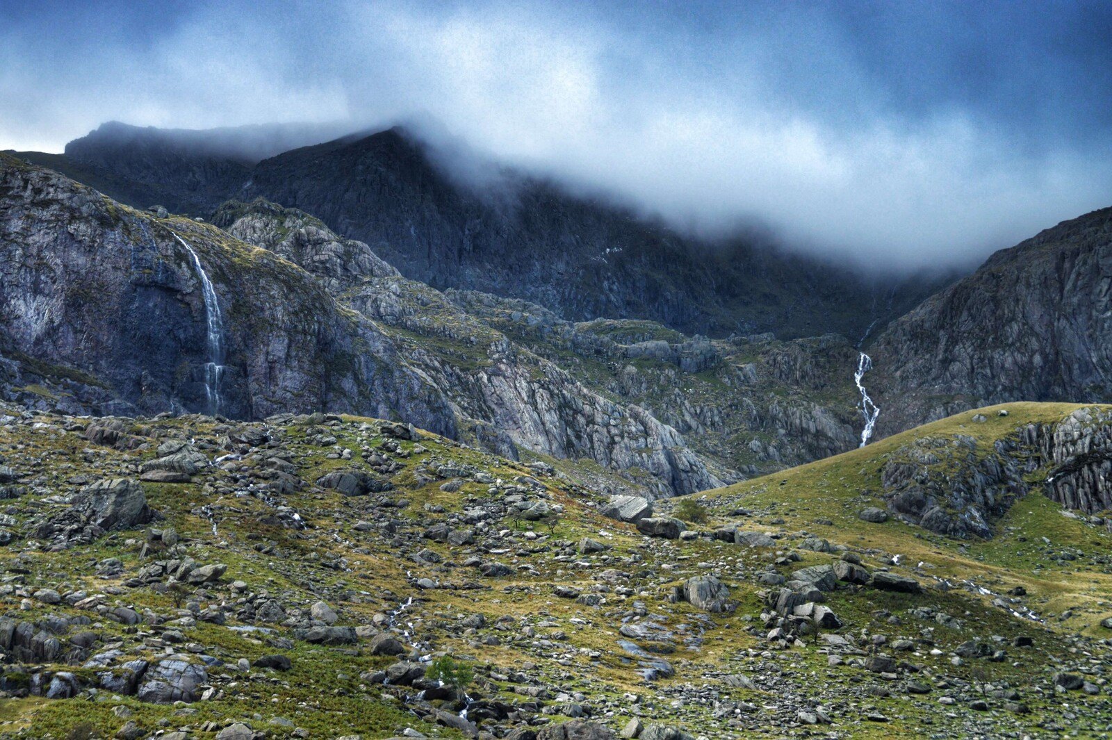 Misty mountain landscape with waterfalls under a cloudy sky